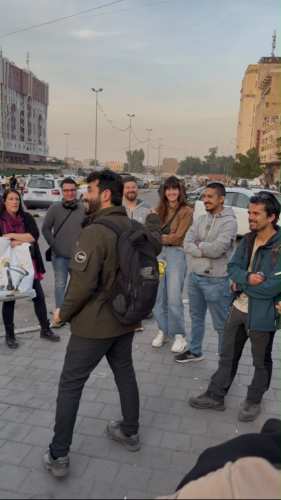 Osamah Mousa speaking to a group in front of a historic Baghdad building